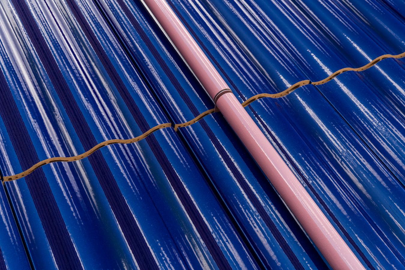 Lähikuva aaltoilevasta sinisestä seinäpinnasta, jonka poikki kulkee vaaleanpunainen palkki.