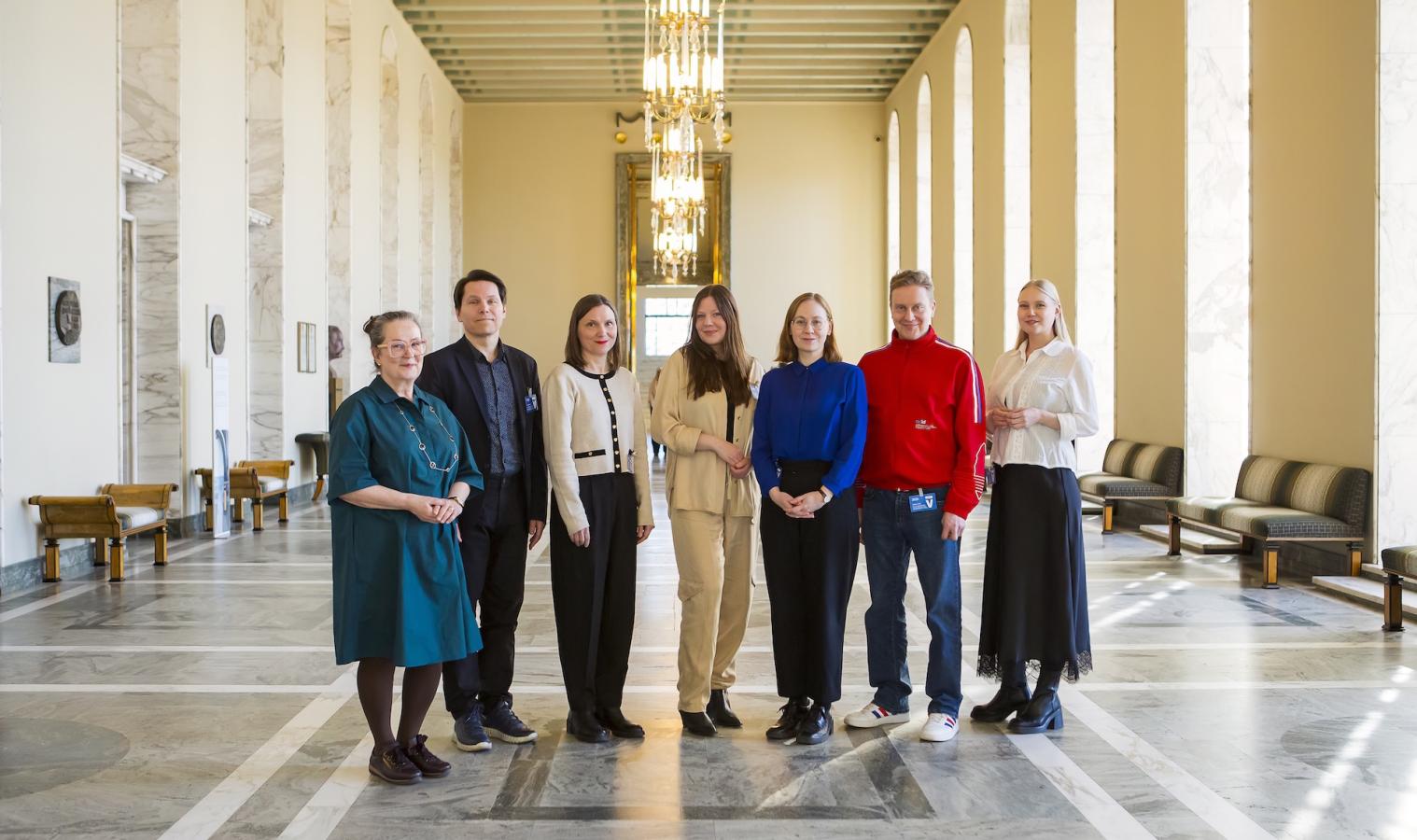 Suomen Taiteilijaseuran ja Kuvaston henkilökuntaa sekä kuvataidekummit Teemu Mäki, Hannaleena Heiska ja Virpi Vesanen-Laukkanen kuvattuna eduskunnan salissa