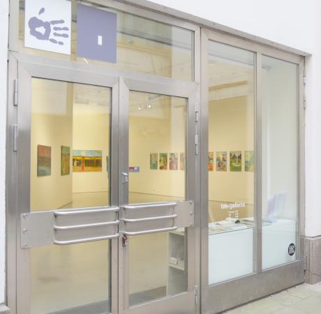Tm gallerian sisäänkäynti. Lasiovi, jonka takana taideteoksia.