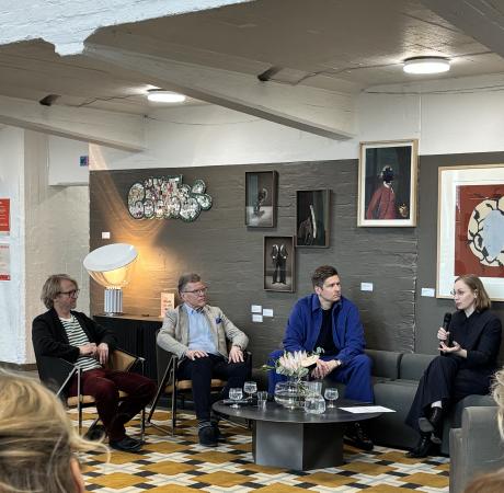 Neljä henkilöä keskustelee taideteosten edessä